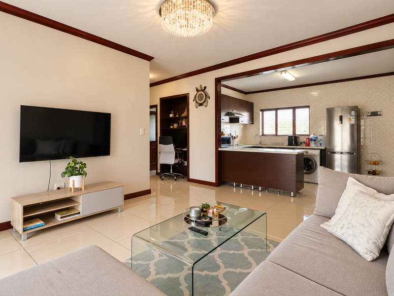 Spacious open-plan living area featuring polished tiled floors, crown molding, and a modern kitchen with integrated cabinetry and a functional island.
