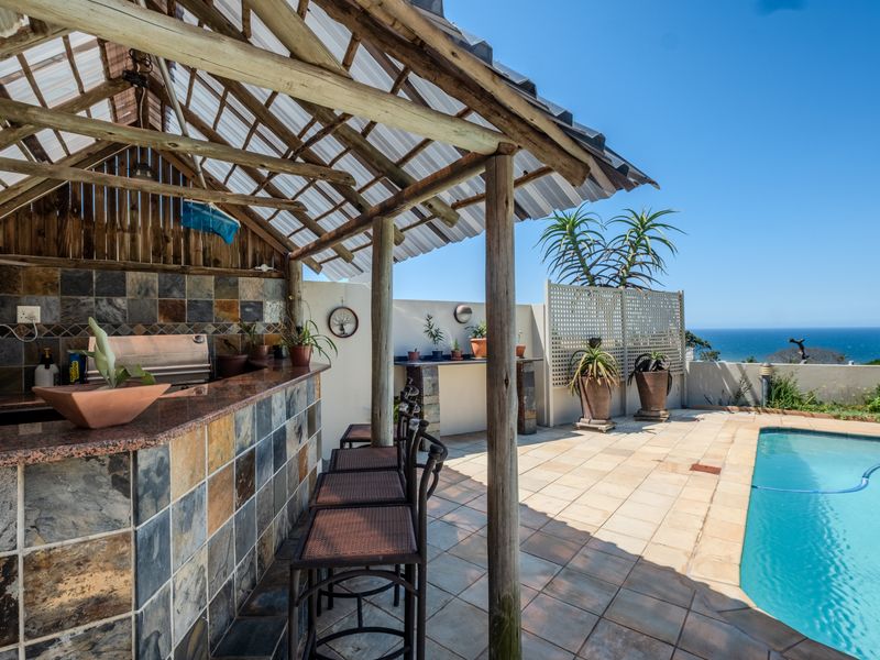 Outdoor entertainment area featuring a covered patio with a built-in braai, granite bar counter, and swimming pool with ocean views.