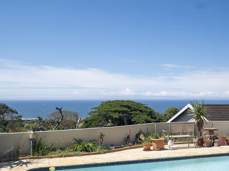 Outdoor pool area featuring a tiled surround and a boundary wall with expansive ocean views.