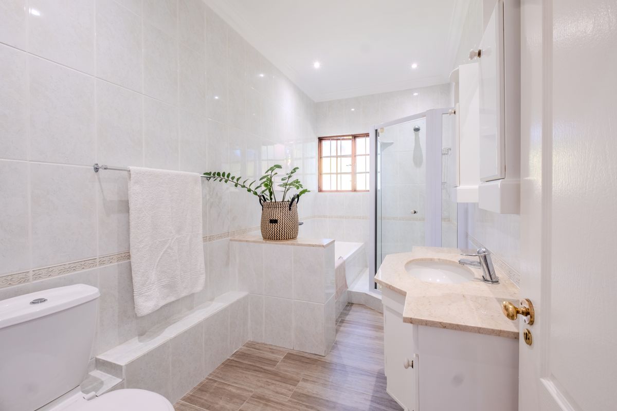 A well-maintained bathroom featuring a built-in vanity with stone countertop, a separate shower enclosure, and a built-in bathtub with neutral wall tiling.