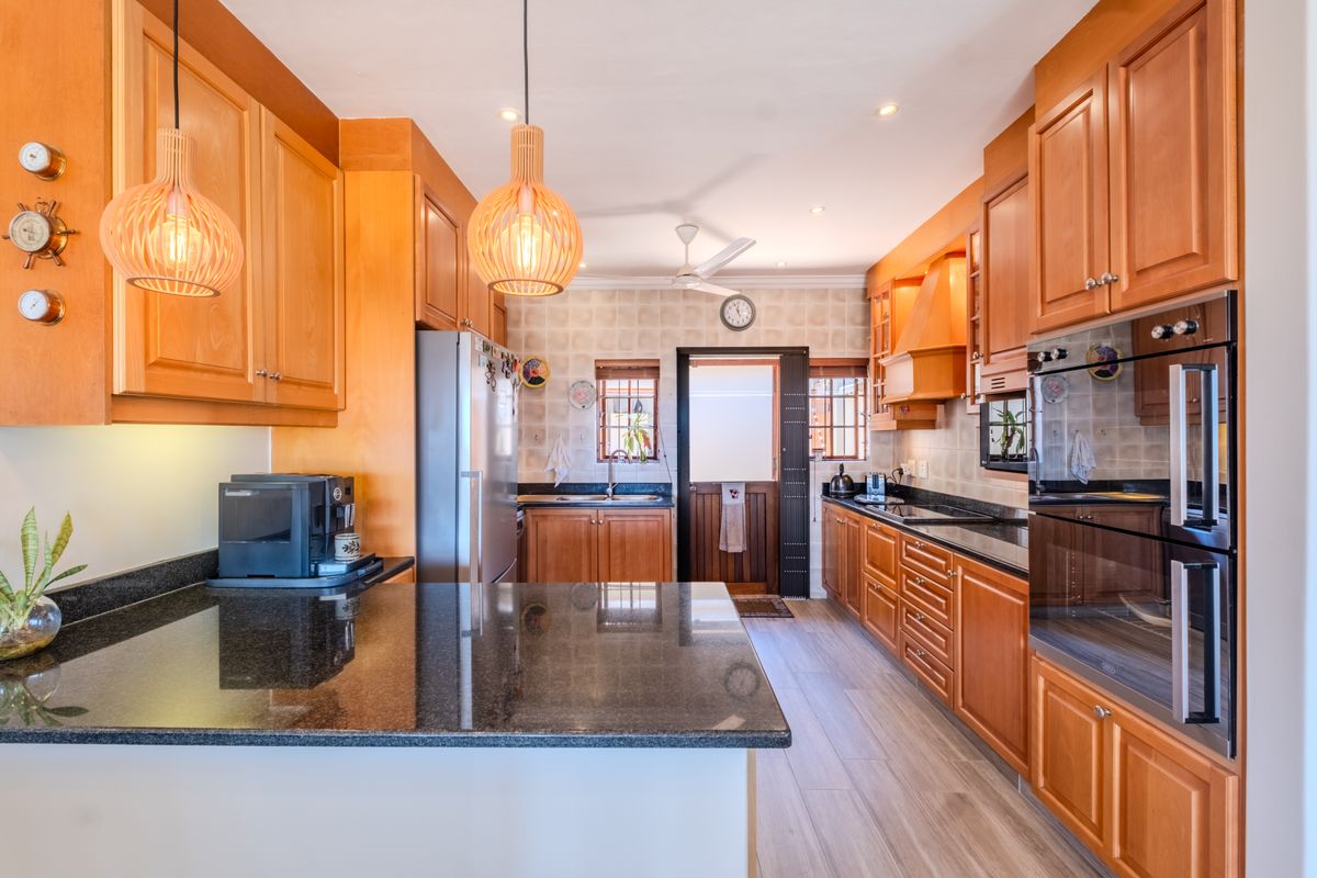 A well-maintained kitchen featuring warm wooden cabinetry, granite countertops, a built-in double oven, and a functional layout with ample storage space.