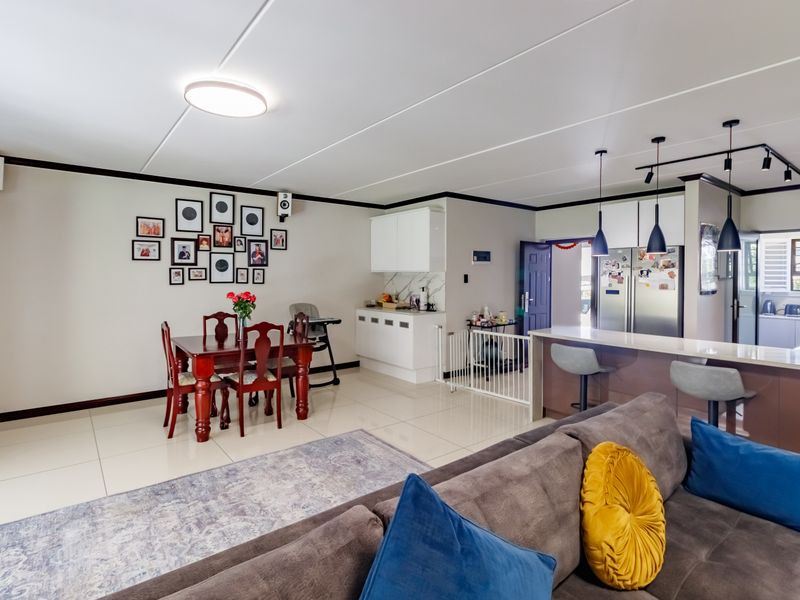 Spacious open-plan living and dining area featuring a modern kitchen with a central island, stone countertops, and contemporary pendant lighting.
