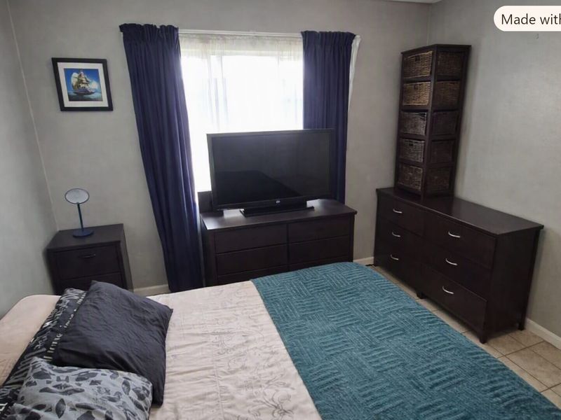 A bedroom featuring tiled flooring and a window with curtains, providing a functional space for rest.