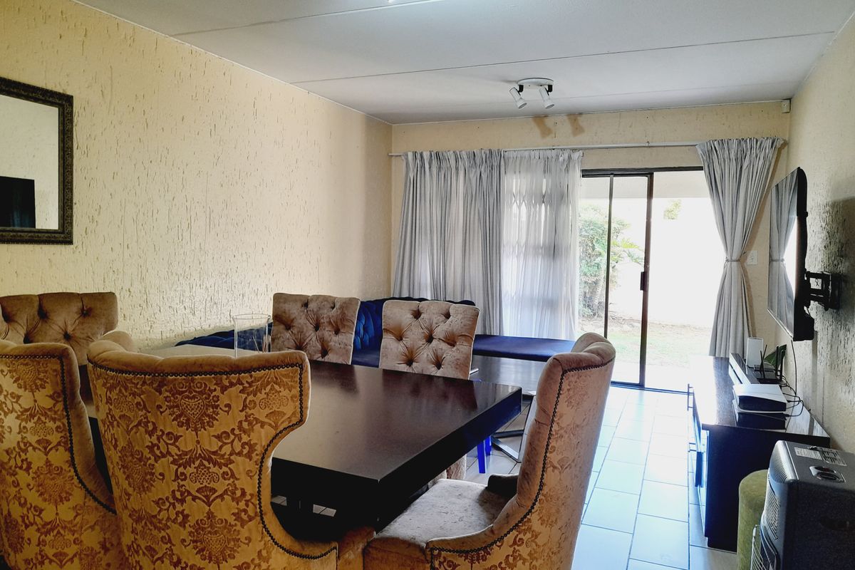 Living and dining area featuring tiled flooring, textured walls, and sliding glass door access to the exterior, with visible ceiling water damage.