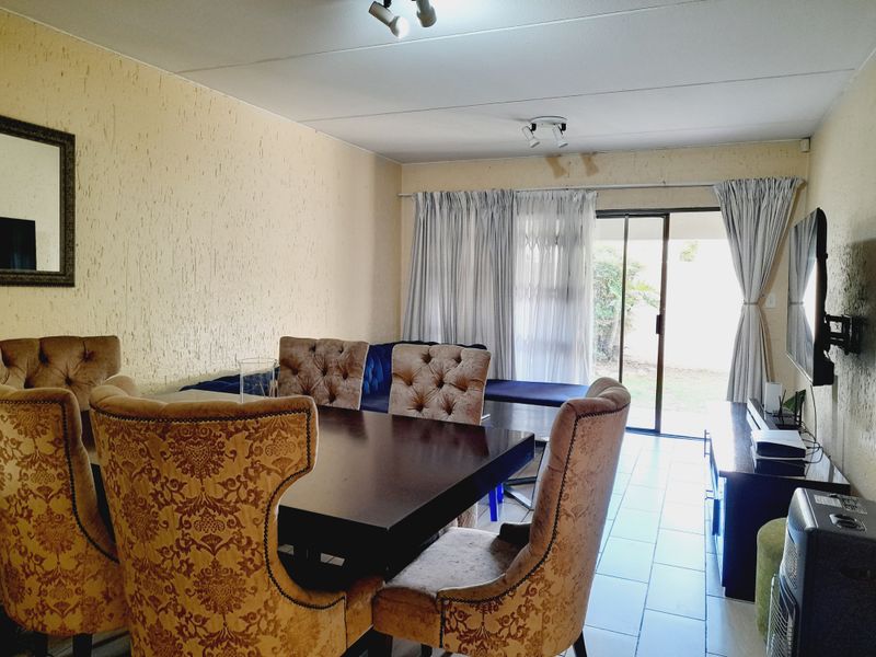 Living and dining area featuring tiled flooring, textured walls, and sliding glass door access to the exterior, with visible ceiling water damage.