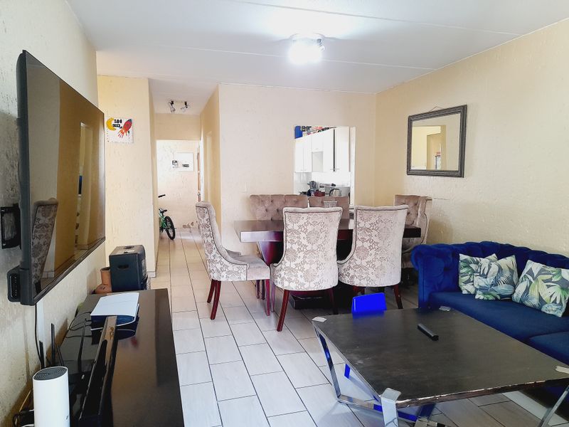 Open plan living and dining area featuring tiled flooring and a pass-through window connecting to the kitchen space.