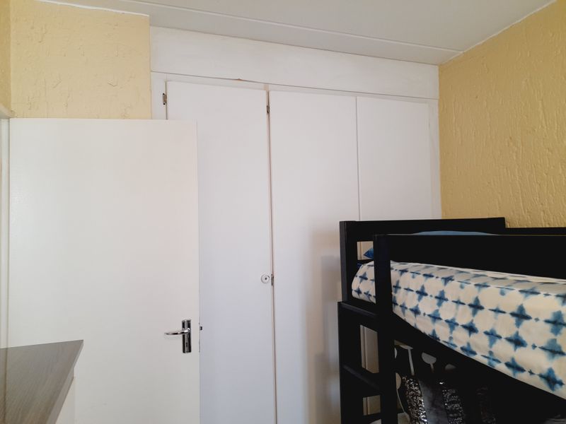 A bedroom featuring built-in cupboards with white doors and textured yellow walls.