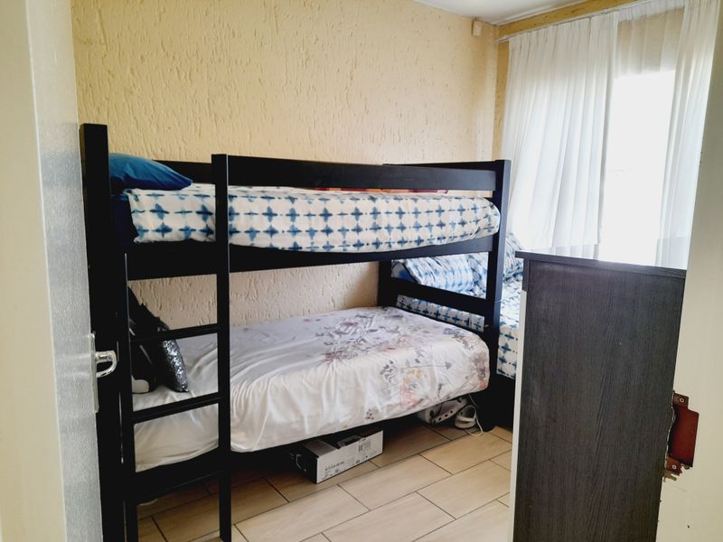 A bedroom featuring tiled flooring and textured walls, currently configured with bunk beds.