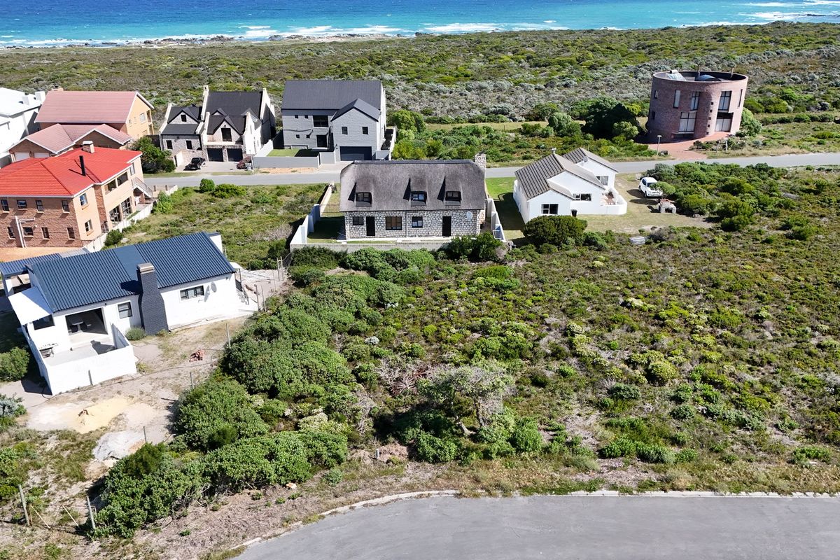 An aerial view of a coastal residential area featuring established homes, natural vegetation, and proximity to the ocean.