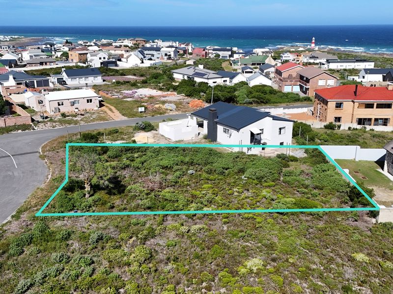 An aerial view of a vacant residential plot in a coastal neighborhood, highlighting the land boundaries and surrounding residential development.