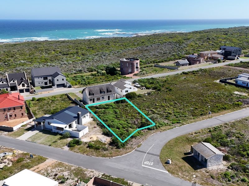 Aerial view of a vacant residential plot situated in a coastal neighborhood, offering proximity to the ocean and established surrounding homes.