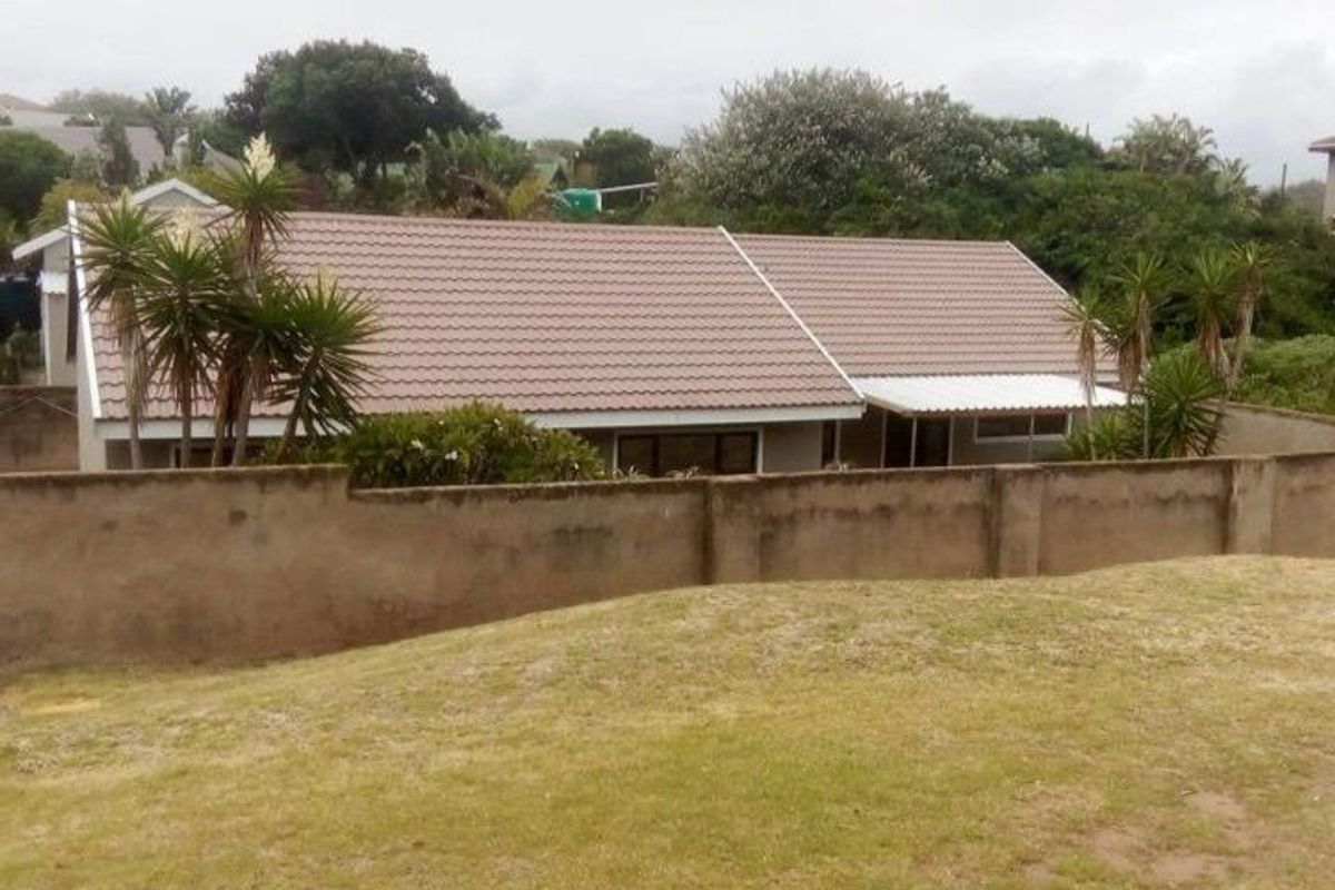 Rear view of the townhouse featuring a tiled roof, a perimeter boundary wall, and a covered patio area.
