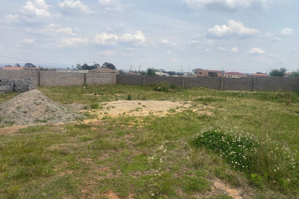 A vacant residential plot featuring a perimeter boundary wall and open, undeveloped land, suitable for future construction projects.