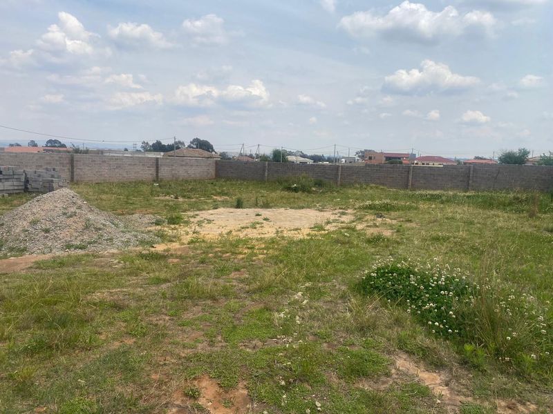 A vacant residential plot featuring a perimeter boundary wall and open, undeveloped land, suitable for future construction projects.