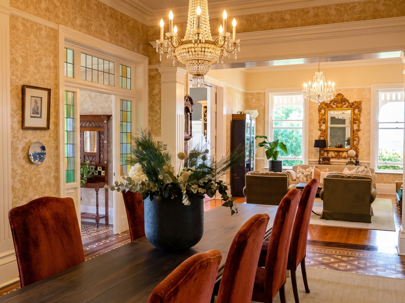 Elegant open-plan living and dining area featuring classic architectural details, crystal chandeliers, fluted columns, and intricate hardwood flooring with decorative inlay.