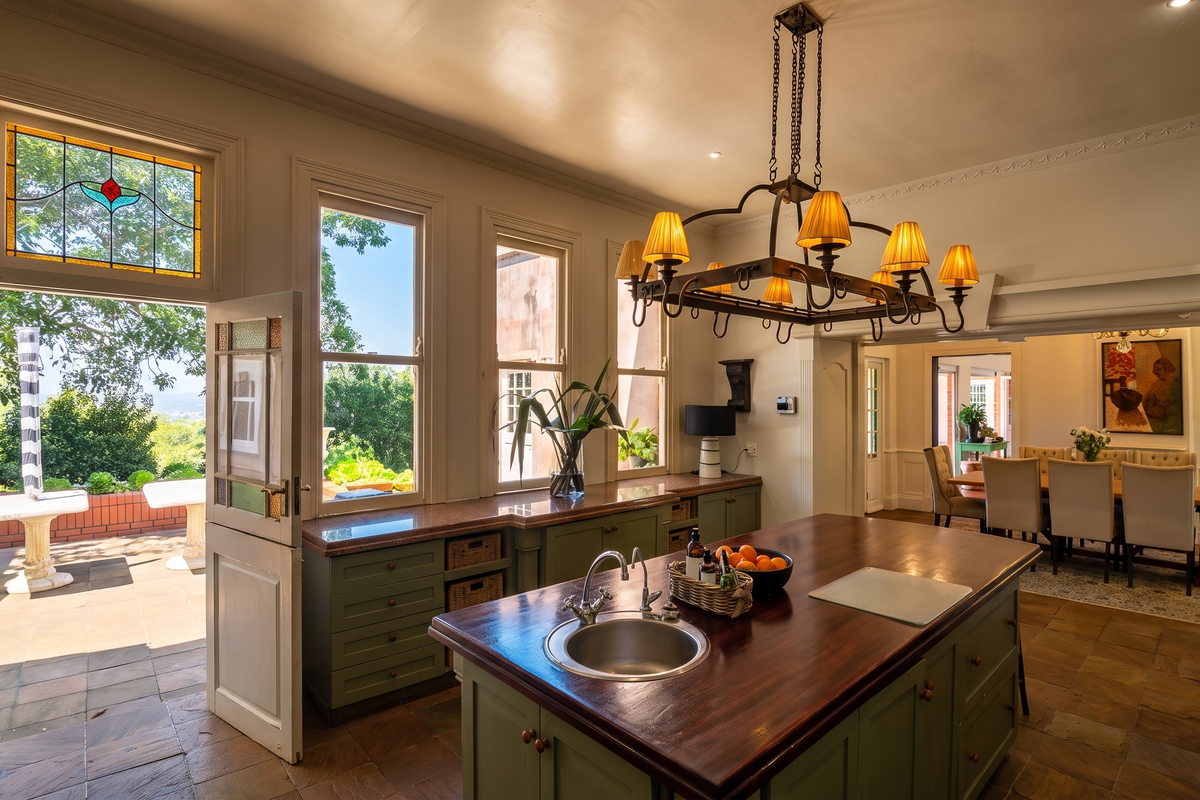 Spacious kitchen featuring a large island with a wooden countertop, custom cabinetry, stone flooring, and direct access to an outdoor patio area.