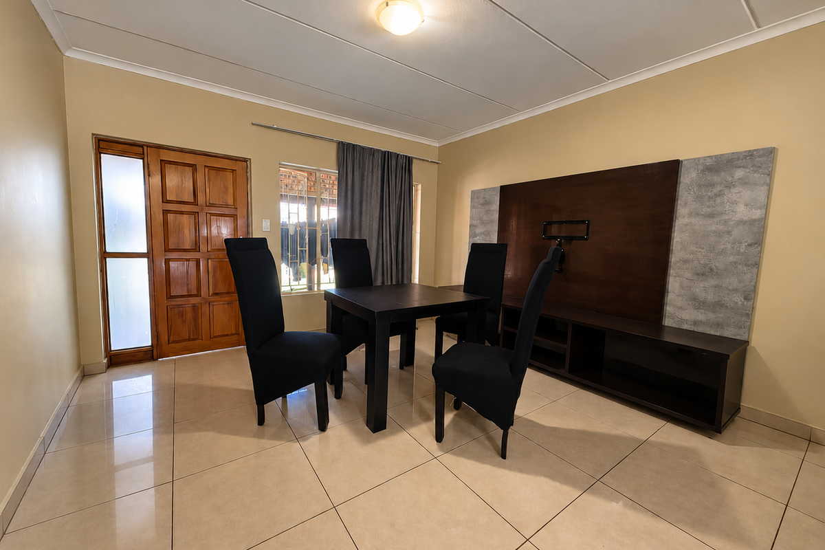 A well-maintained living area featuring large format floor tiles, a built-in media console, and a solid timber entrance door.