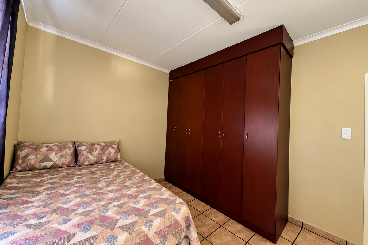 A bedroom featuring tiled flooring and a large, dark wood built-in wardrobe providing ample storage space.