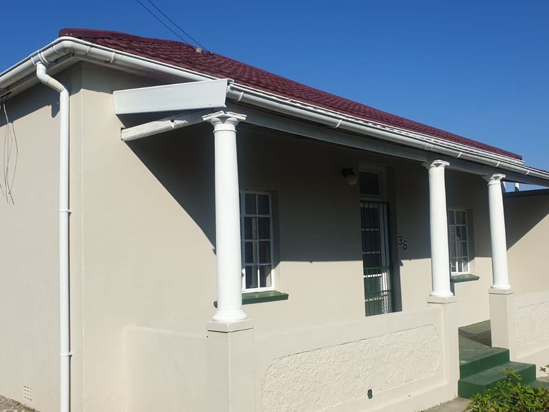 Front elevation of a house featuring a covered porch with classical columns, pitched roof, and security gate entrance.