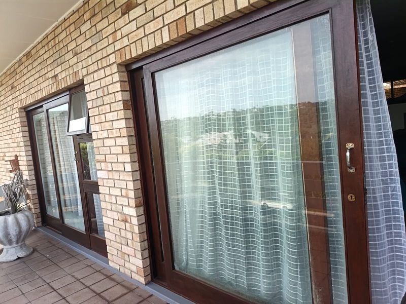 A covered balcony area featuring brick exterior walls and dark-framed sliding glass doors leading into the apartment.