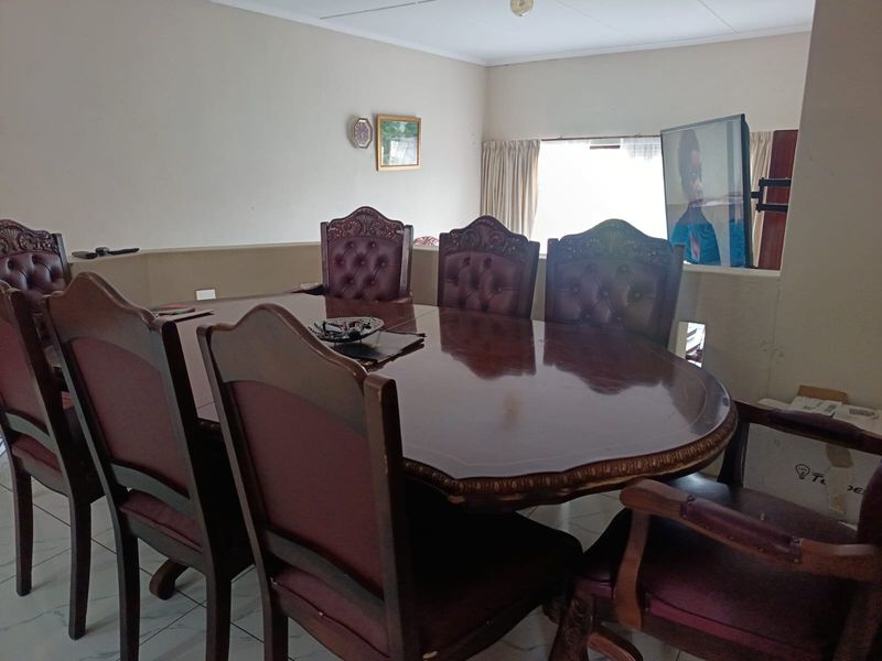 A dining room area featuring tiled flooring and a window with curtain tracks, providing a functional space for meals.