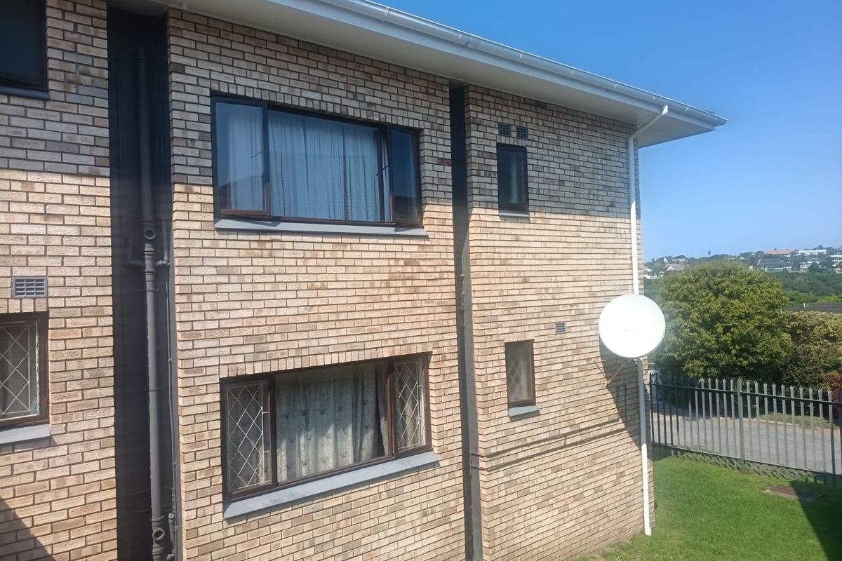 Exterior view of the apartment building featuring brick facade, aluminium window frames, and a satellite dish installation.
