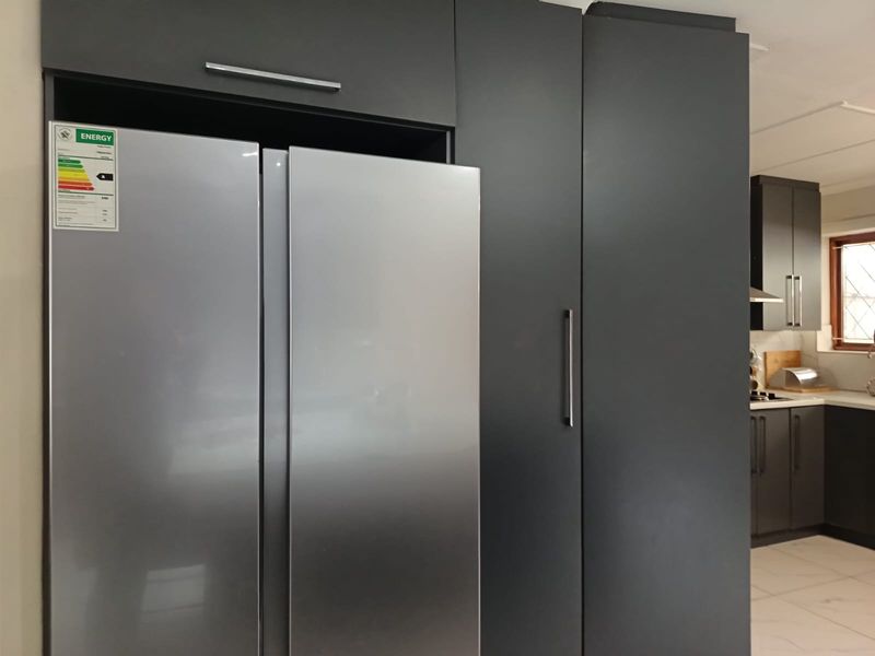 Modern kitchen featuring sleek dark cabinetry, integrated appliance housing, and clean tiled flooring, offering a contemporary and functional culinary space.