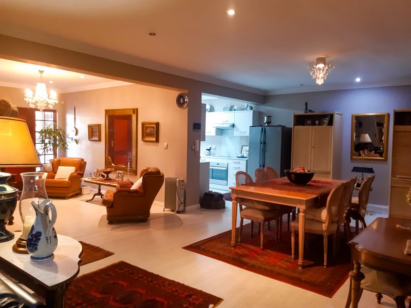 Spacious open-plan living and dining area featuring recessed lighting, chandeliers, and a view into the adjacent kitchen with built-in cabinetry and appliances.