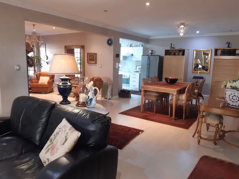 Spacious open-plan living and dining area featuring neutral tones, recessed lighting, and a functional kitchen with built-in cabinetry and appliances.