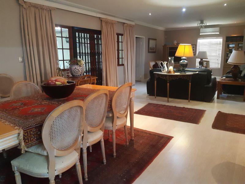 Spacious open-plan living and dining area featuring light laminate flooring, recessed downlighting, and a wall-mounted air conditioning unit.