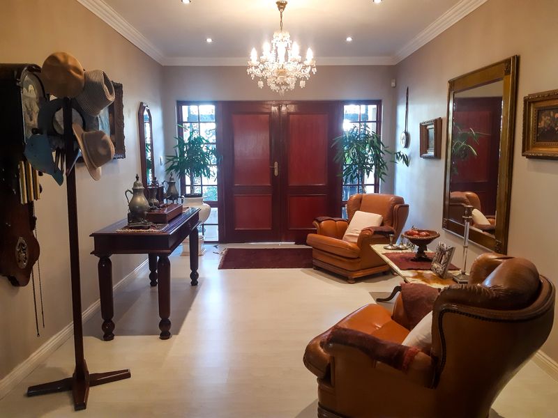 A welcoming entrance hall featuring double doors, elegant chandelier lighting, coved ceilings, and neutral tiled flooring.
