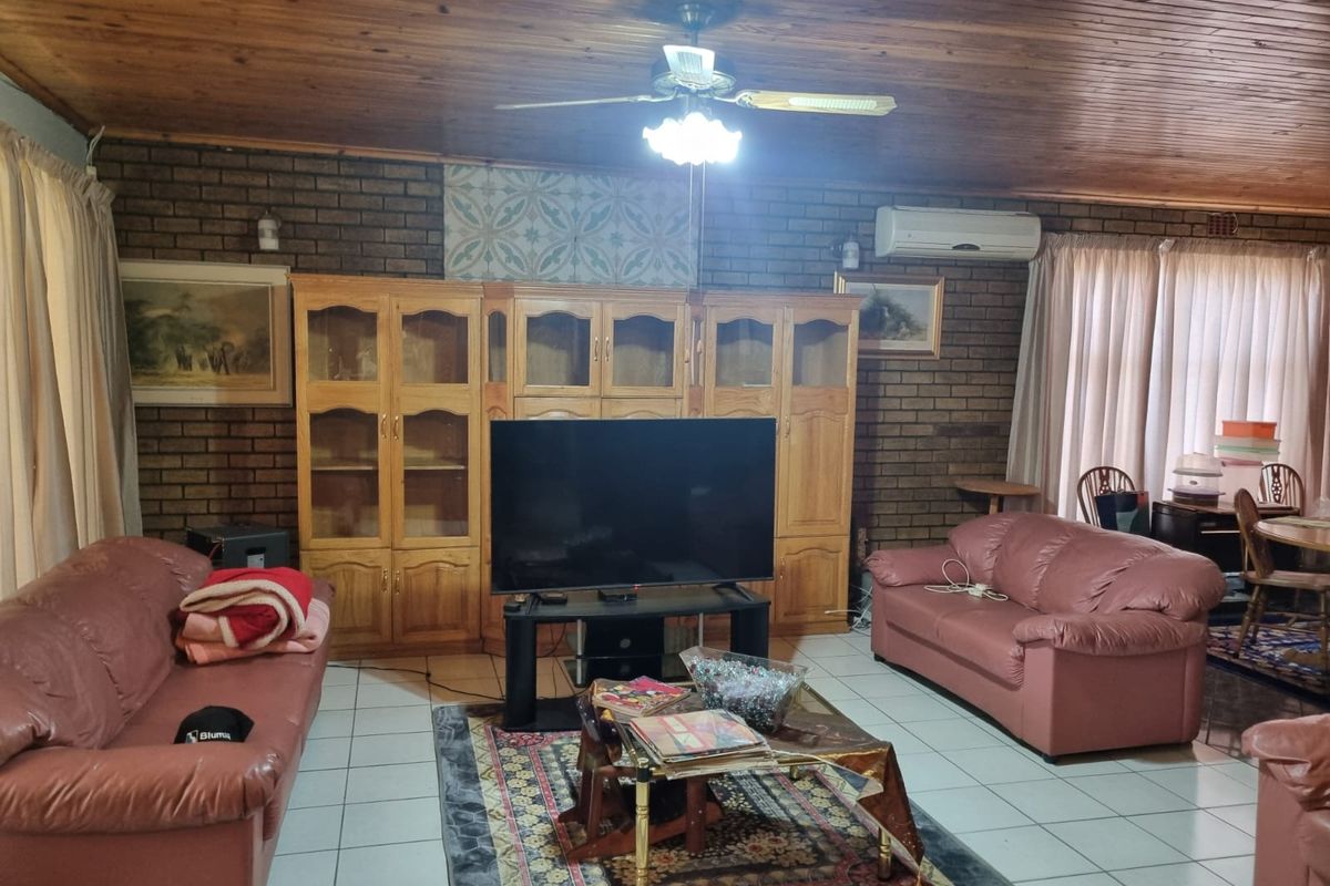 Spacious living room featuring exposed brick walls, a timber-clad ceiling, tiled flooring, and a wall-mounted air conditioning unit.
