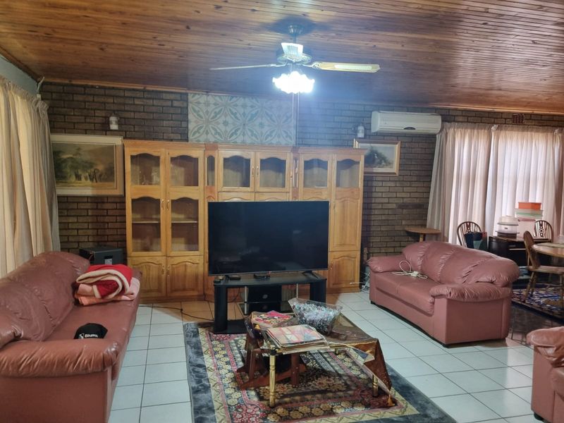 Spacious living room featuring exposed brick walls, a timber-clad ceiling, tiled flooring, and a wall-mounted air conditioning unit.