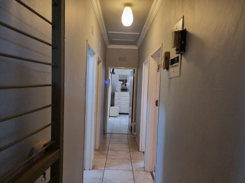 A functional hallway featuring tiled flooring, ceiling cornicing, and a wall-mounted electrical distribution board, providing access to multiple rooms.