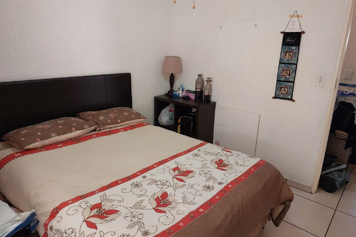 A bedroom featuring tiled flooring and textured walls, offering a functional space ready for cosmetic updates and personalization.