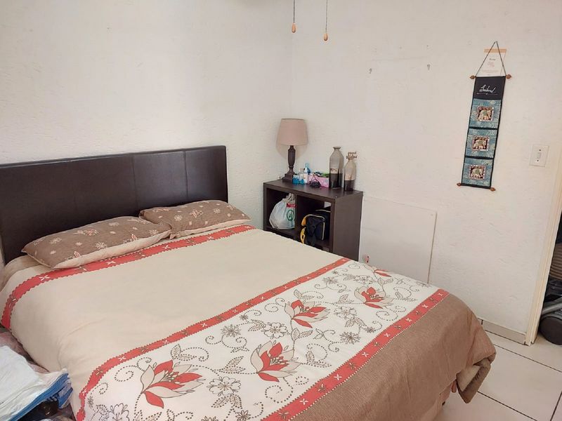 A functional bedroom featuring tiled flooring and textured walls, providing a neutral base for potential interior updates.