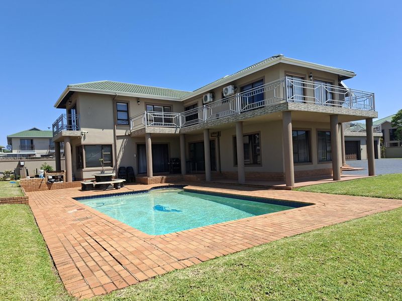 Spacious rear exterior featuring a swimming pool, brick paved surround, and a large upper-level balcony with metal railings.