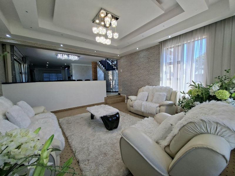 Spacious living room featuring a coffered ceiling with recessed lighting, a textured stone feature wall, and an open-plan layout leading to the staircase.