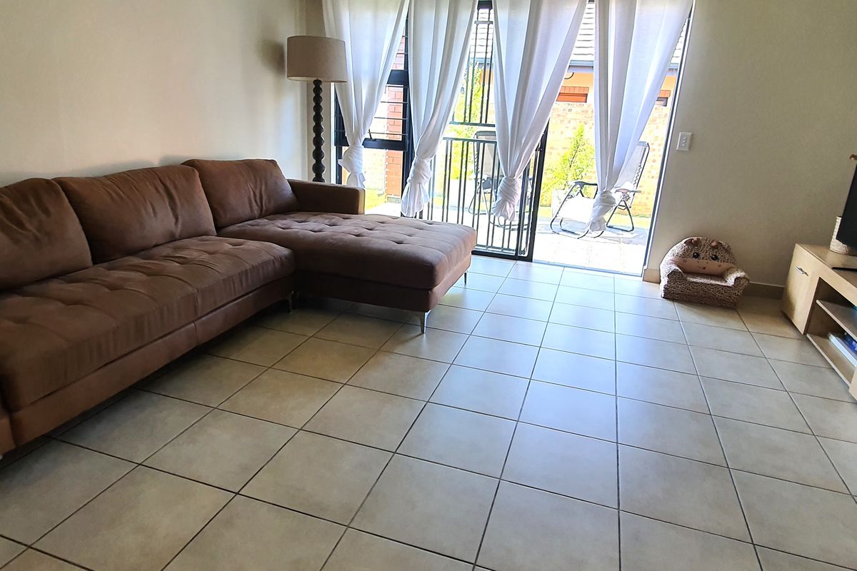A living room featuring tiled flooring and a sliding glass door that provides access to an outdoor patio area.