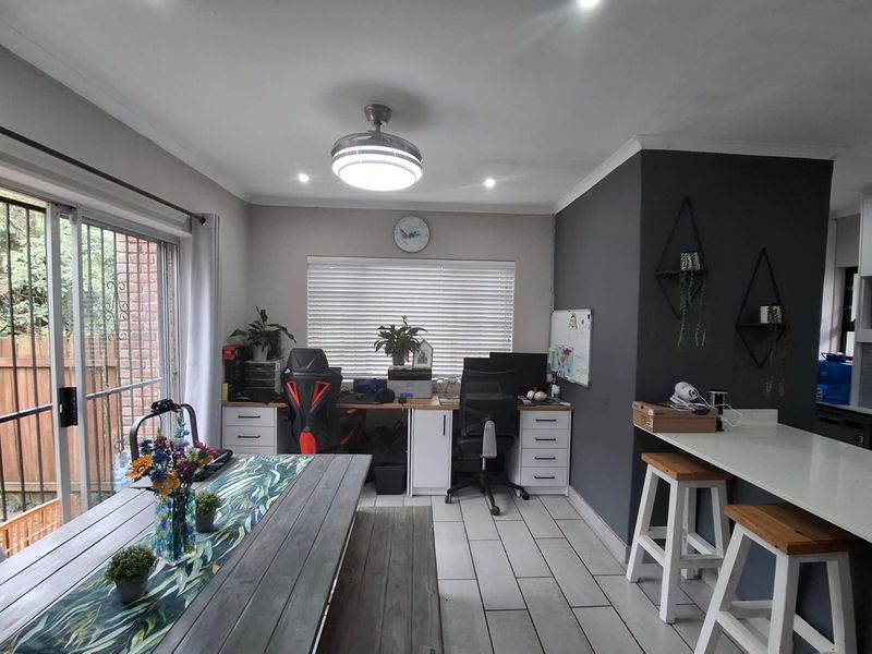 Open-plan living area featuring a built-in home office workstation, stone breakfast bar, tiled flooring, and sliding door access to the exterior.