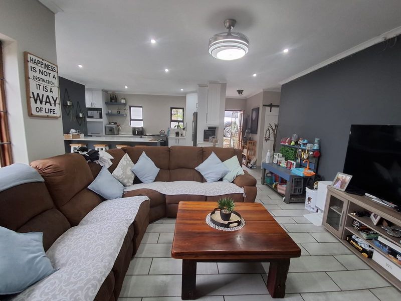 Spacious open-plan living area featuring tiled floors, recessed lighting, and a modern kitchen with a central island and built-in appliances.
