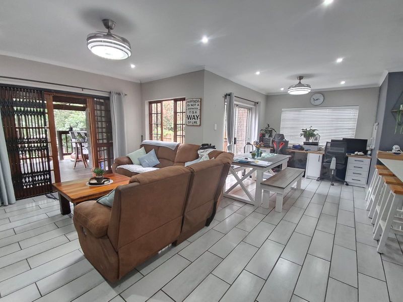 Spacious open-plan living area featuring tiled flooring, recessed lighting, ceiling fans, and direct access to an outdoor patio through sliding glass doors.