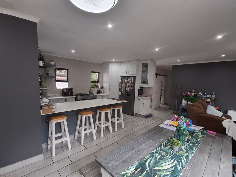Spacious open-plan kitchen and living area featuring a central island, modern cabinetry, gas hob, and tiled flooring throughout.