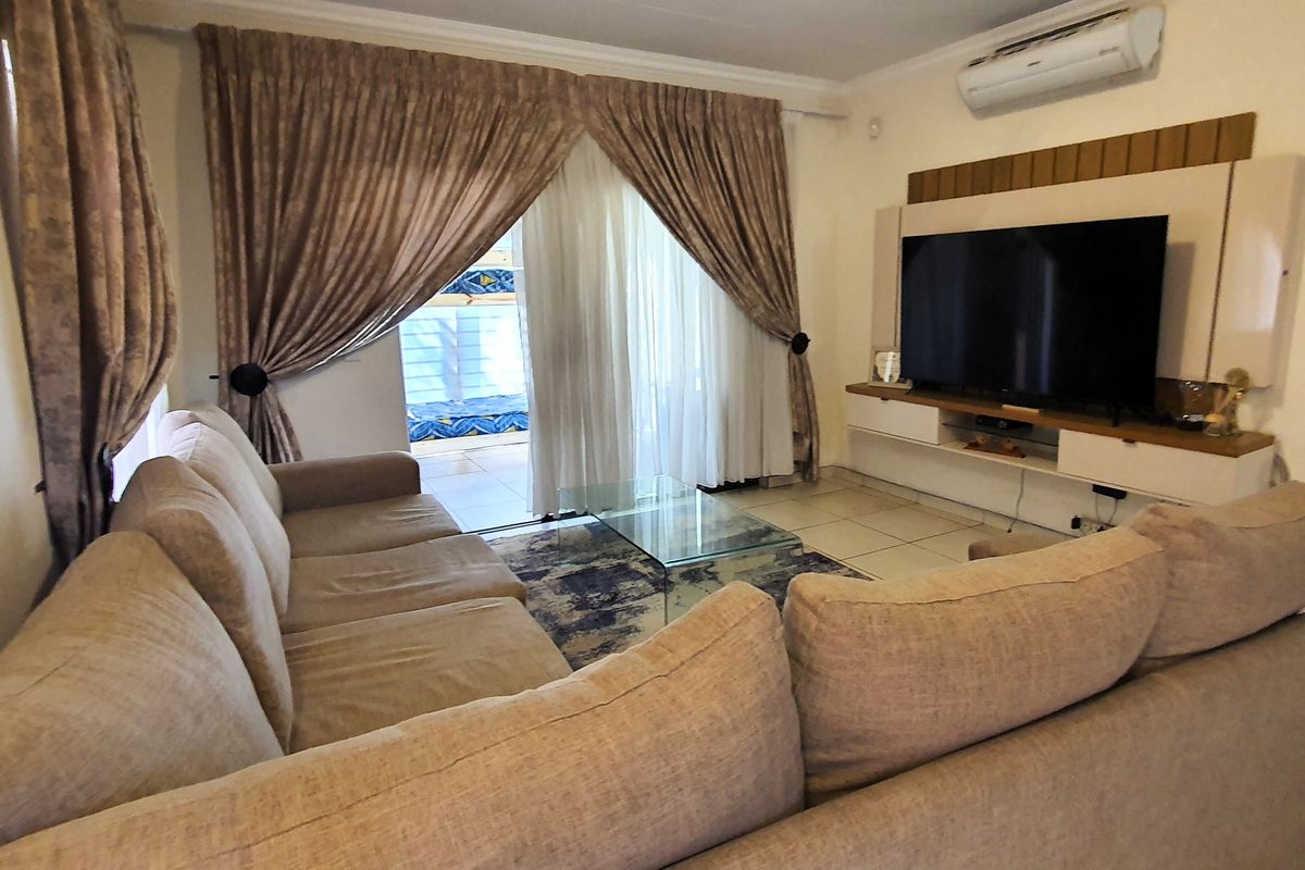 A comfortable living room featuring tiled flooring, a built-in media console, and a sliding glass door providing access to the patio area.