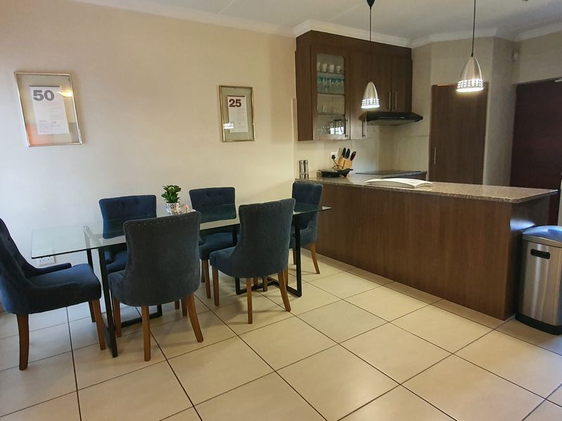 Open-plan living and dining area featuring a modern kitchen with granite countertops, wooden cabinetry, and tiled flooring throughout.