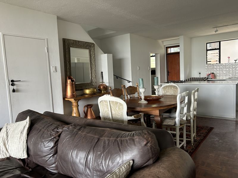 Open plan living and dining area featuring parquet flooring, a kitchen island with built-in cabinetry, and a staircase leading to the upper level.