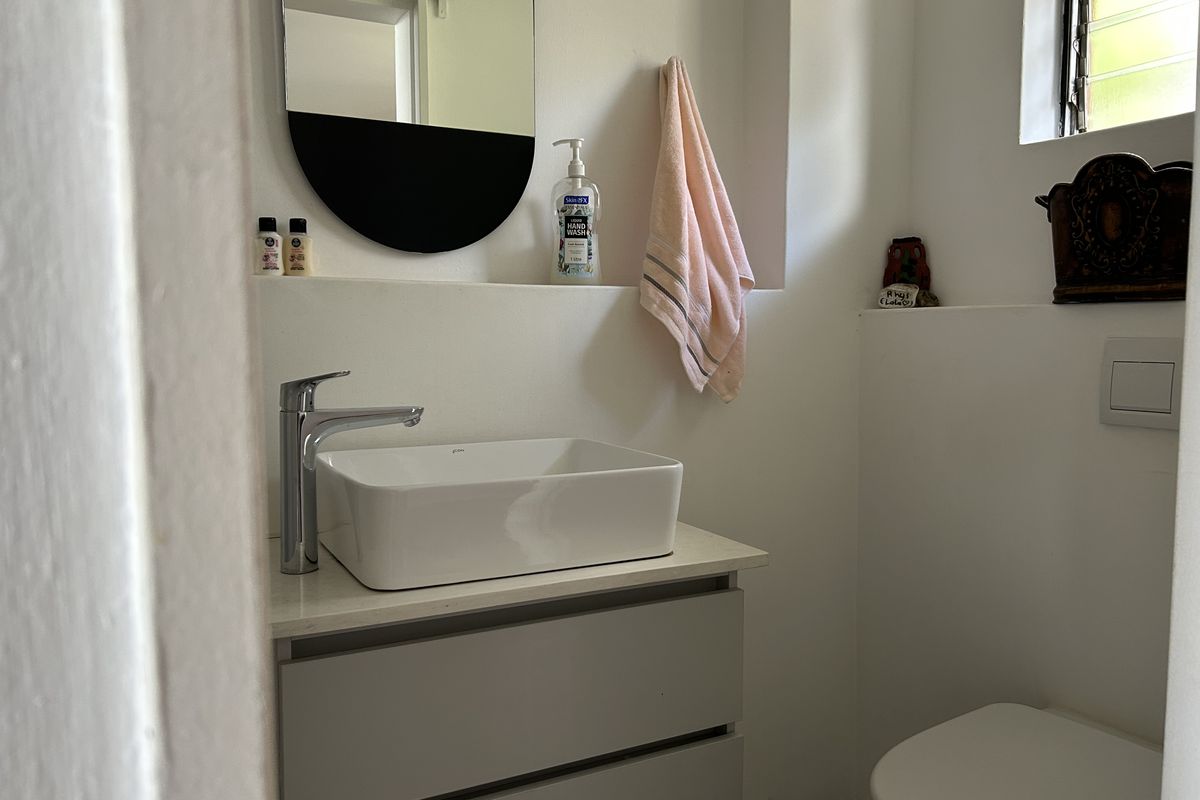 A modern bathroom featuring a sleek vessel sink on a vanity cabinet, wall-mounted toilet, and a convenient recessed shelf for storage.