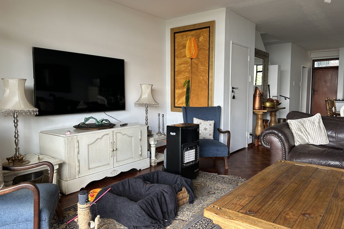 A comfortable living room featuring warm parquet flooring and neutral wall finishes, providing a versatile space for relaxation and entertainment.