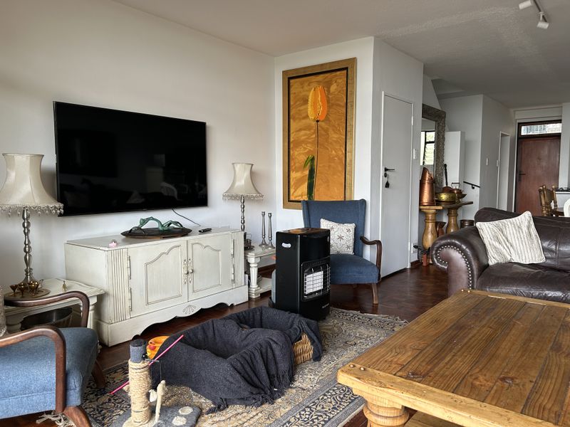 A comfortable living room featuring warm parquet flooring and neutral wall finishes, providing a versatile space for relaxation and entertainment.