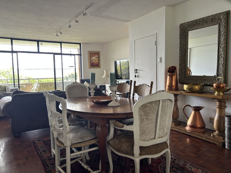 Open plan living and dining area featuring parquet flooring, track lighting, and large sliding glass doors leading to a balcony.